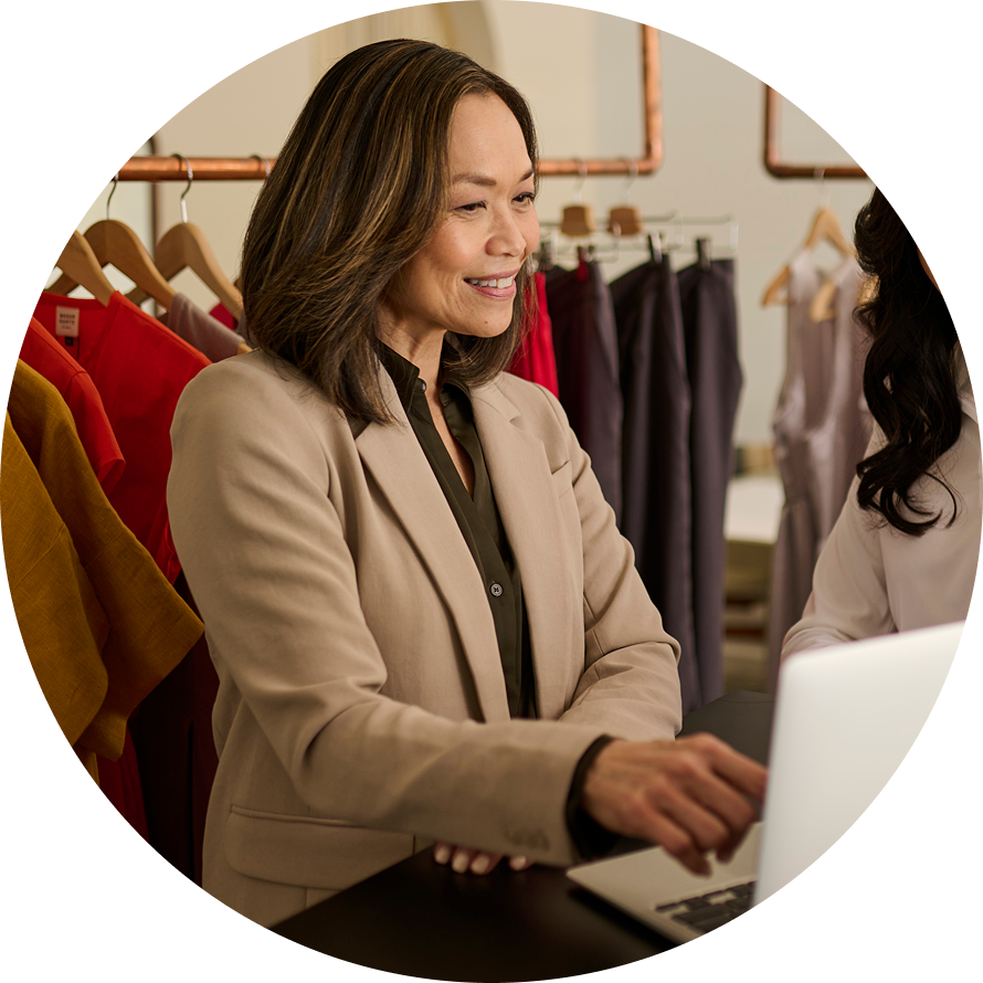 Retail worker using laptop in cothing boutique
