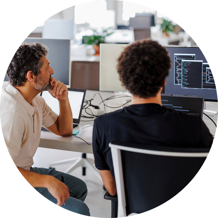 Two coworkers collaborating and reviewing code on a computer in an office
