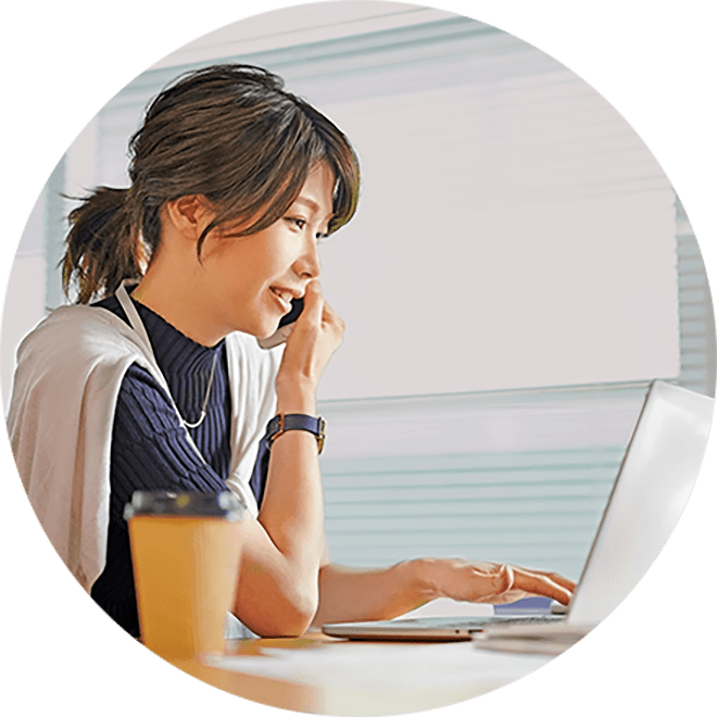 woman talking on the phone and looking at her laptop at her office